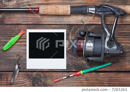 fishing tackle and photo frame on wooden table 7265263