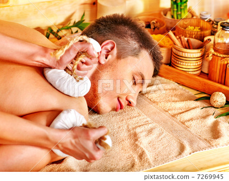 Man getting herbal ball massage treatments . 7269945