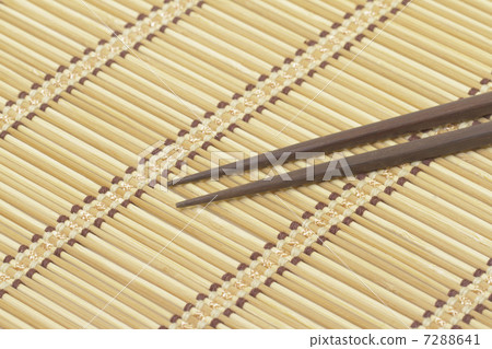 Dark wooden chopsticks on bamboo mat 7288641