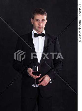 Stylish man in elegant black tuxedo with glass red wine 7289521