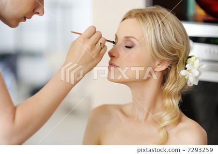 Young beautiful bride applying wedding make-up 7293259