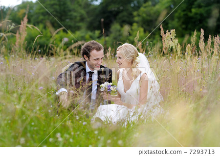 Bride and groom sitting in a meadow Bride and groom sitting in a meadow 7293713