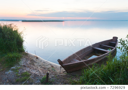 Sunset with old flooding boat on summer lake shore 7296929