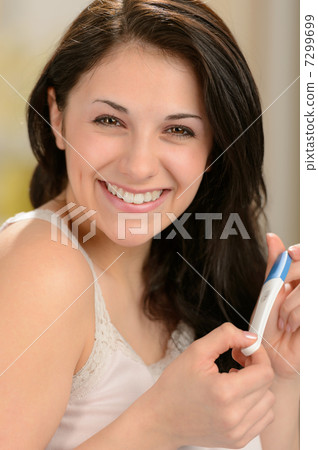 Cheerful young woman holding pregnancy test Cheerful young woman holding pregnancy test 7299699