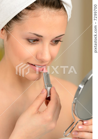 Young teenager girl using lipstick handheld mirror Young teenager girl using lipstick handheld mirror 7299700