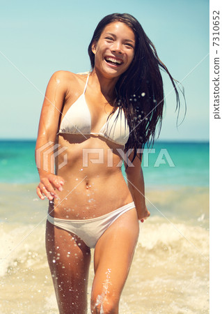 Beach bikini woman walking laughing happy in water 7310652