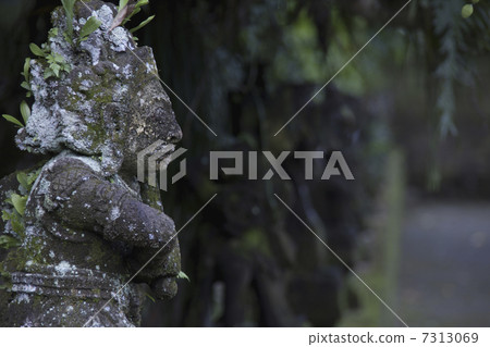 A stone statue standing in a quiet and mossy space 7313069