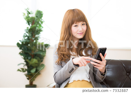 A woman who uses a smartphone in a room 7332887