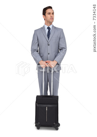 Serious young businessman waiting with his luggage Serious young businessman waiting with his luggage 7334148