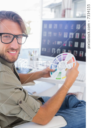Photo editor holding colour wheel and smiling at camera 7334155