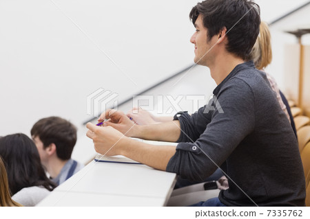 Student sitting in a lecture hall and listening the teacher Student sitting in a lecture hall and listening the teacher 7335762
