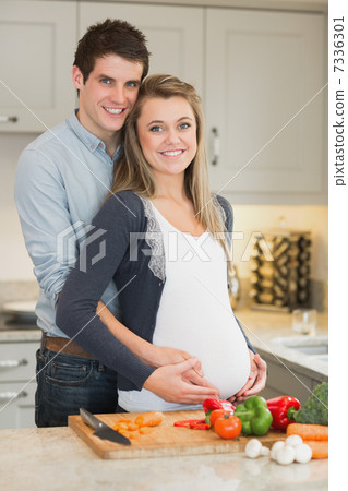 Pregnant woman and huband stand behind kitchen counter 7336301