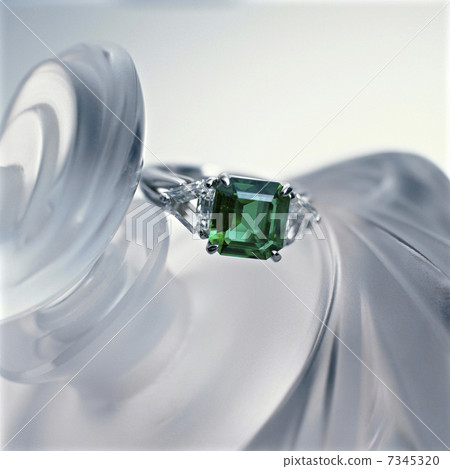 An emerald ring placed on a perfume bottle 7345320