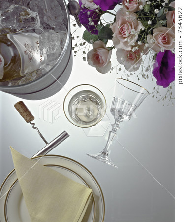 An overlooking table with a flower arrangement on a wine cooler and a glass 7345622