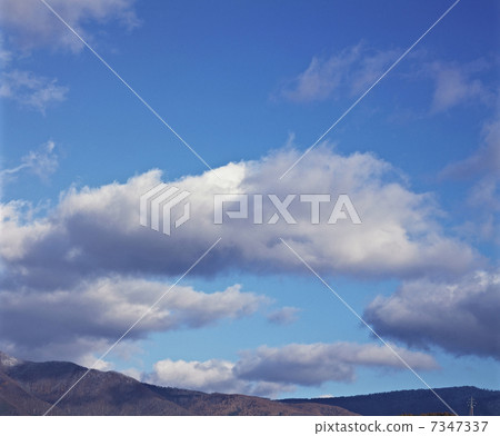 Above the mountains, the clouds floating in the blue sky Above the mountains, the clouds floating in the blue sky 7347337