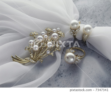 Pearl accessories entangled with tulle on marble Pearl accessories entangled with tulle on marble 7347341