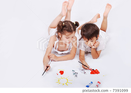 Beautiful scene of a girl and boy laying and playing with colors on ground Beautiful scene of a girl and boy laying and playing with colors on ground 7391099