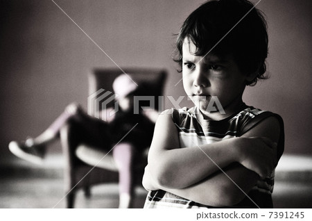 Old style photography: angry boy standing in front of relaxed girl in chair. Black and white photo, darkness, and a lot of grain added for desired effect. Old style photography: angry boy standing in front of relaxed girl in chair. Black and white photo, darkness, and a lot of grain added for desired effect. 7391245