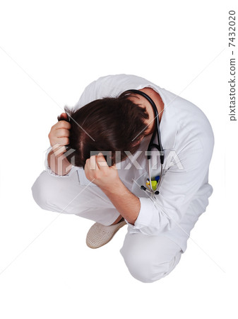 Young male doctor sitting down with hands on his head 7432020