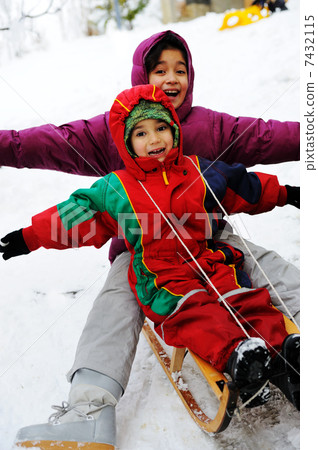 children have fun together sliding downhill on a pleasant winter day 7432115