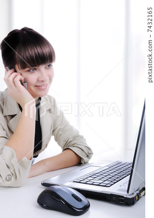 Portrait of a young woman on phone in front of a laptop computer 7432165