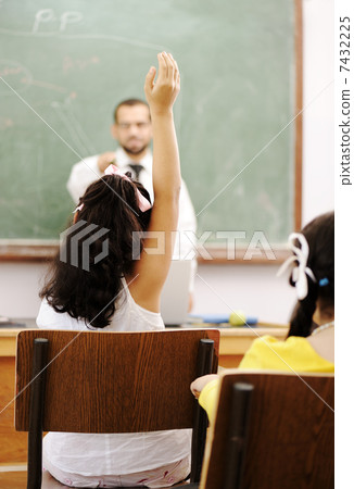 Teacher and pupil in school, hand rising and answering 7432225