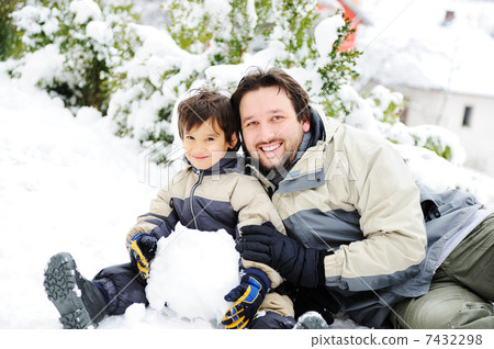 Father and son playing happily in snow making snowman, winter season 7432298