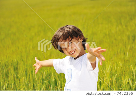 Happy kid on green field with widely opened arms 7432396