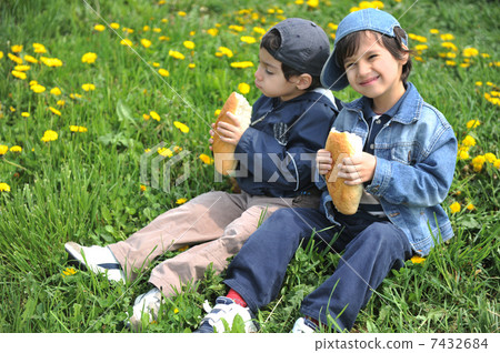 Two little friends eating together, outdoors 7432684