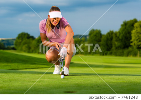 Young female golf player on course aiming for her put 7461248