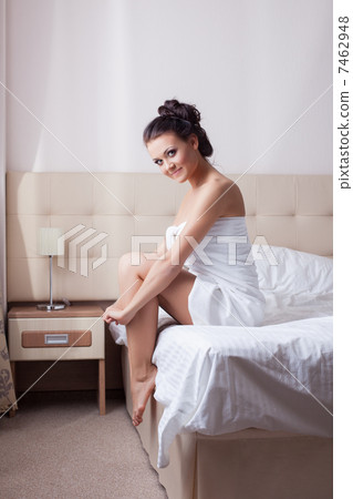 Smiling brunette sitting on hotel bed 7462948