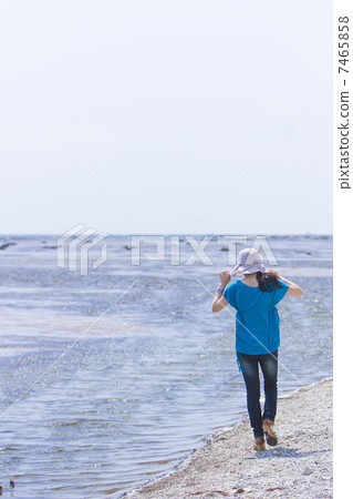 A woman walking along the beach A woman walking along the beach 7465858