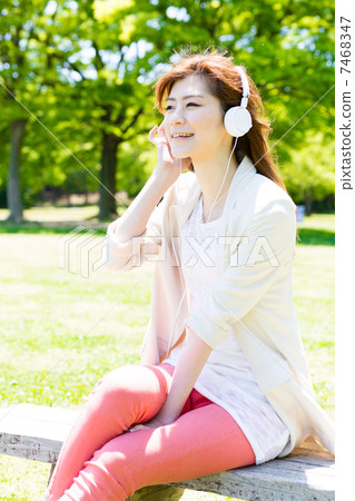 一個女人在公園聽音樂 7468347