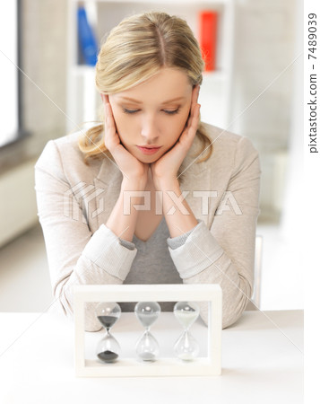 pensive businesswoman with sand glass 7489039