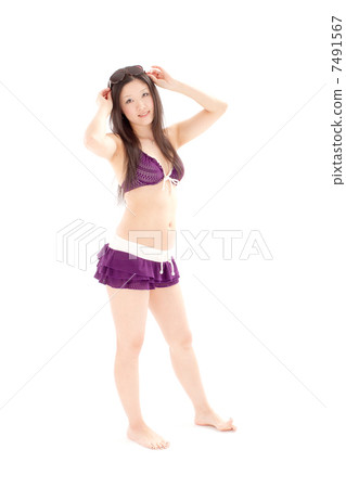 A beautiful woman in swimsuit watching sunglasses standing on top of the forehead 7491567