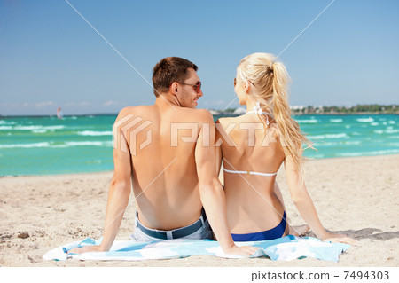happy couple sitting on the beach 7494303
