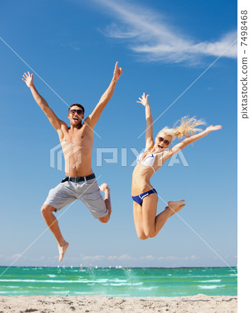 happy couple jumping on the beach 7498468