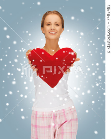 happy and smiling woman with heart-shaped pillow 7498485