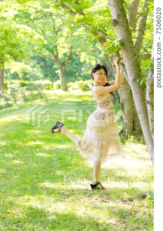拿著一個逗人喜愛的姿勢的新鮮的綠色女孩舉行在一棵樹在初夏森林裡 7506020