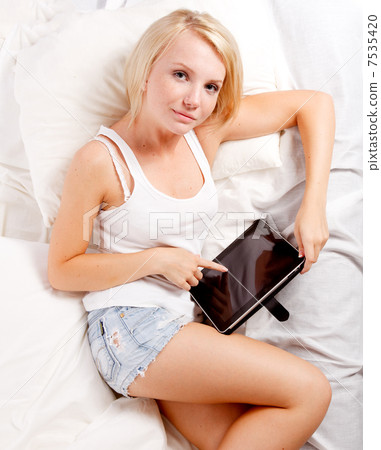 Young woman lying on the bed with tablet pc 7535420