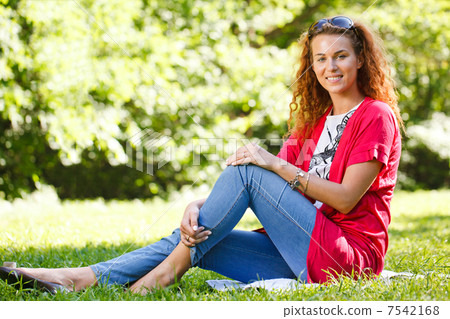 Woman sitting on grass in park 7542168