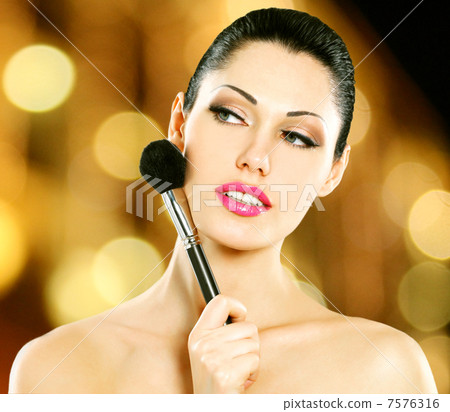 Beautiful woman applying blusher on face 7576316
