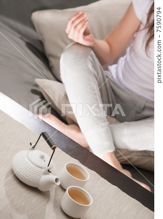 Young woman sitting in meditation pose in front of tea set. Rela Young woman sitting in meditation pose in front of tea set. Rela 7590794