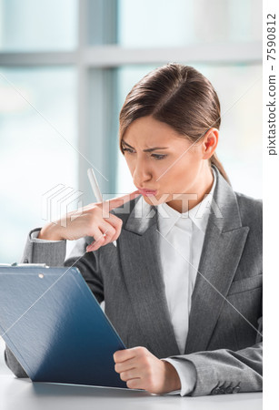 Front view of business woman looking over papers on clipboard at 7590812