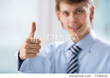Happy smiling young business man with thumbs up gesture at his o Happy smiling young business man with thumbs up gesture at his o 7590816