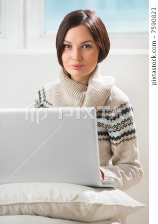 A young woman sitting on the floor in front of her laptop, looki A young woman sitting on the floor in front of her laptop, looki 7590821