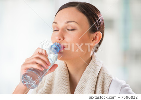 Portrait of young woman drinking water at gym after doing exerci Portrait of young woman drinking water at gym after doing exerci 7590822