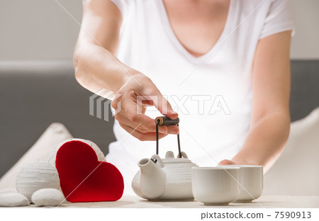 Detail shot of female arm holding tea pot and welcoming to joing Detail shot of female arm holding tea pot and welcoming to joing 7590913