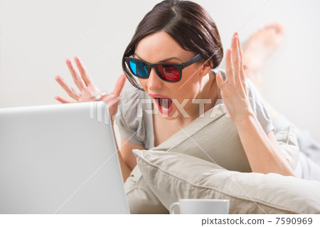 A young woman lying on the floor in front of her laptop with cup 7590969