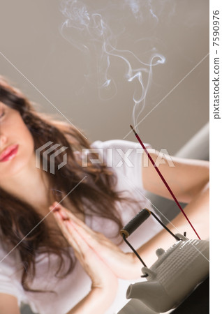 Young woman sitting in meditation pose in front of tea set and a 7590976